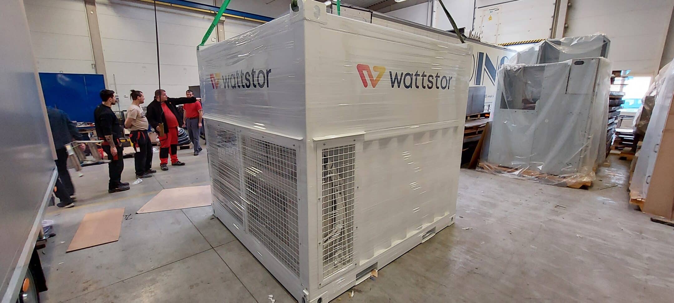 Bateriové úložiště od společnosti Wattstor pro Hrvatska Elektroprievreda v Chorvatsku, pohled na zabalené úložiště ve skladu s dělníky kolem, připraveno k přepravě.