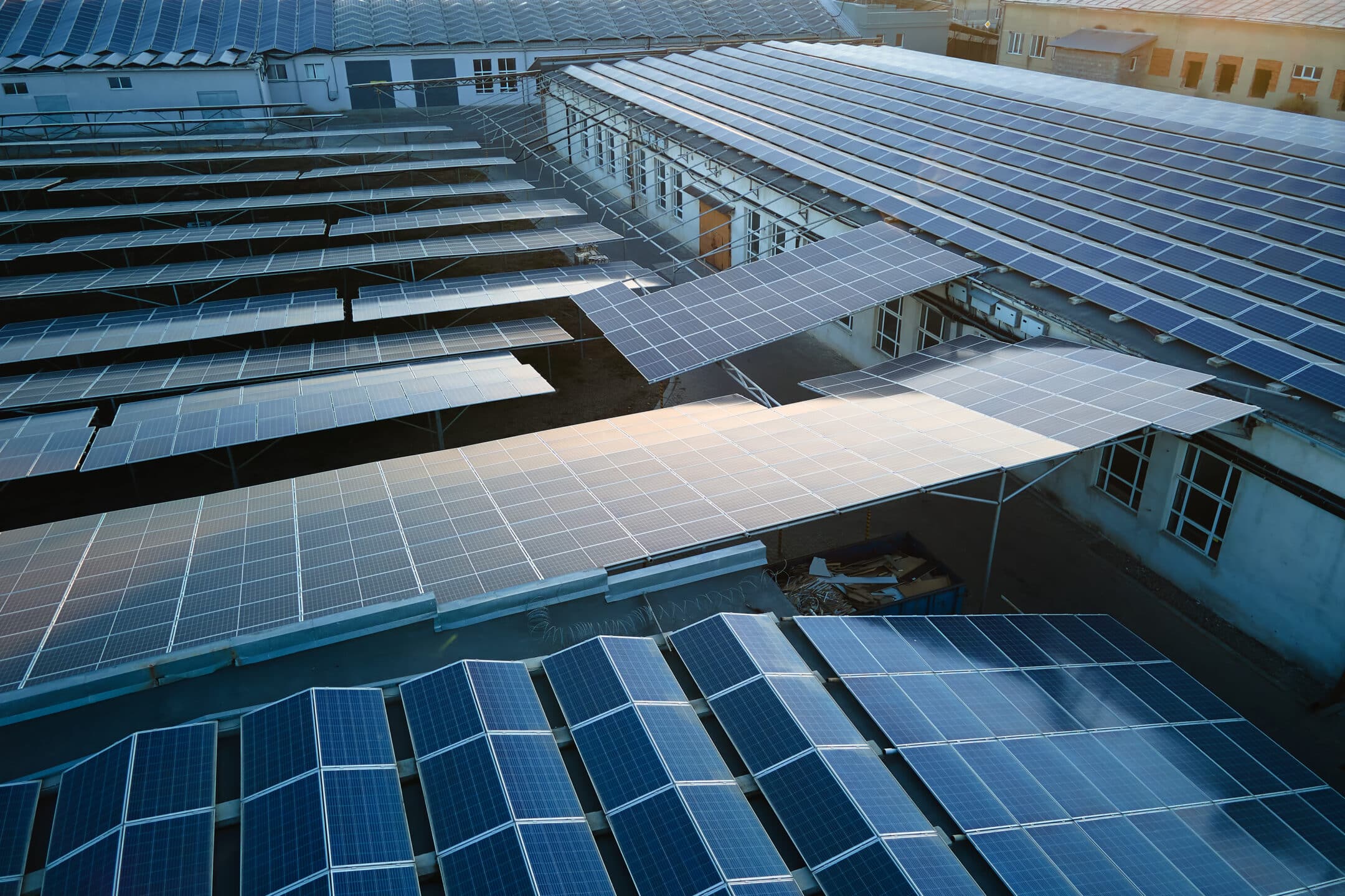Aerial view of blue photovoltaic solar panels mounted on industrial building